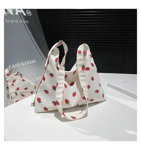 Dettaglio della borsa tote in tela con stampa fragola e tracolla larga riflessa nello specchio