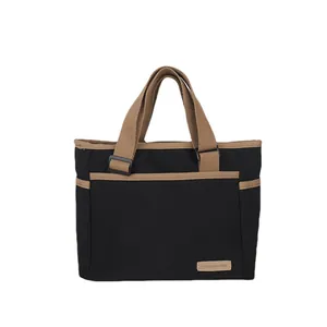 Sac fourre-tout minimaliste en toile noire avec anses brunes et poche avant