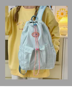 Detalle de mochila azul claro con cordones rosas y parche de logotipo en cuero suave