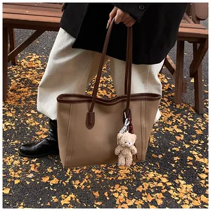 Close-up of brown textured leather tote bag with brown straps and cute bear charm outdoors