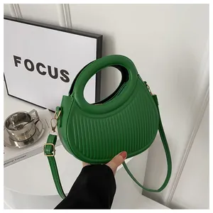 Dettaglio della borsa verde brillante con goffratura a righe verticali e manico tondo