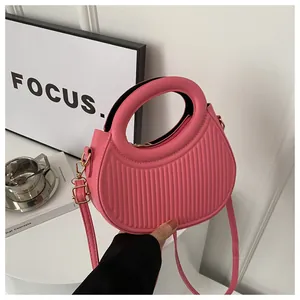 Dettaglio borsa rosa a semicerchio con strisce verticali e finiture metalliche oro