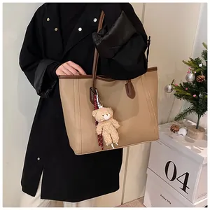 Detail view of beige tote bag with litchi grain texture and brown leather straps