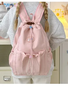 Detalle de mochila rosa con cordón ajustable que incluye bolsillos y parche logo