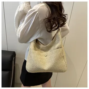 Détail du sac hobo en paille tissé montrant la texture et le fermoir doré en métal
