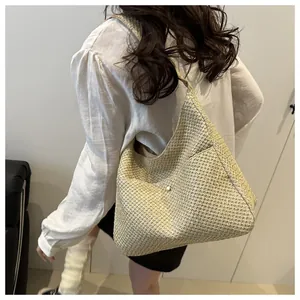 Détail du sac cabas en paille tissée avec bouton blanc élégant et large bandoulière