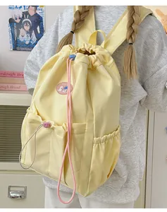 Detalle de una mochila amarillo claro con cordón y parche de dibujos animados decorativo
