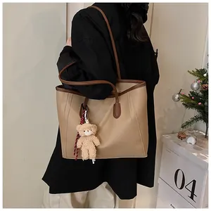 Detail of khaki tote bag with brown straps and cute teddy bear pendant for women
