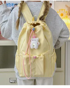 Mochila amarilla clara con cordón, correas anchas y lindo colgante de osito