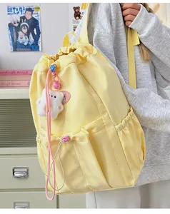 Detalle de mochila de nailon amarilla con cordón y bonito colgante de pata de gato felpa