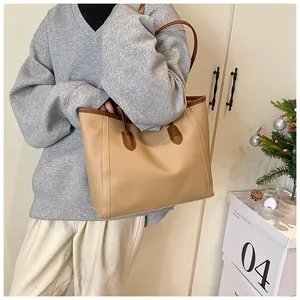 Close-up of contrast brown tote bag showing premium lychee grain leather texture and handle