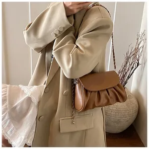 Model wearing a caramel brown pleated crossbody bag with chain strap and PU leather finish