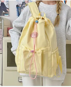 Detalle de mochila amarilla crema con cordón y múltiples bolsillos en un modelo