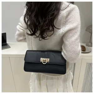 Detail einer schwarzen Vintage-Tasche mit goldenem D-Schloss auf weißem Pullover