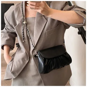 Detail of black pleated crossbody bag with chain strap and metal ball adjuster