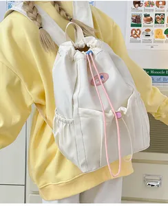 Detalle de mochila de cordón crema con detalles en rosa y bolsillos laterales en modelo