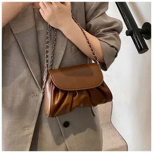 Detail of caramel leather pleated crossbody bag with woven metal chain strap