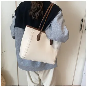 Rear view of a cream tote bag with brown straps worn by a model for a commute look