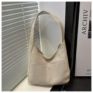 Texture détaillée du sac à bandoulière en paille tressée beige avec bouton doré