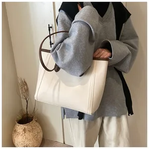 Close-up of cream tote bag with brown straps and detailed pebbled leather texture