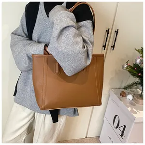 Detailed view of brown large tote bag with pebble leather texture and shoulder strap