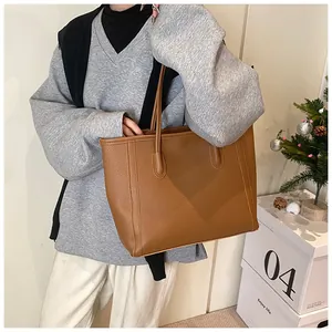 Detail of warm brown tote bag with lychee texture being held by a model for daily commute