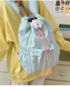 Primer plano de mochila azul claro con cordones rosas y accesorio de colgante de felpa blanco