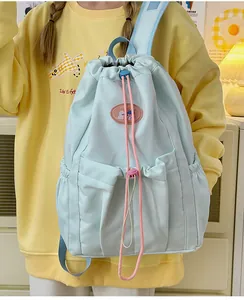 Detalle de la mochila azul claro con cordón, detalles en rosa y tejido impermeable