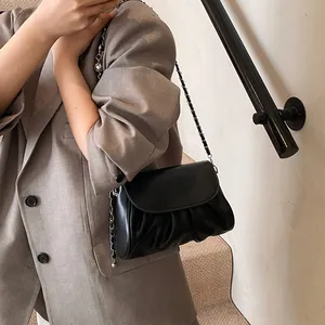 Fashionable black pleated shoulder bag with silver chain strap shown on model's shoulder