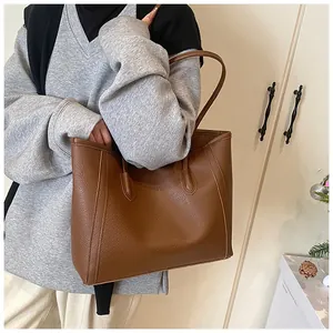 Close-up of brown litchi grain leather texture and stitching on large tote bag