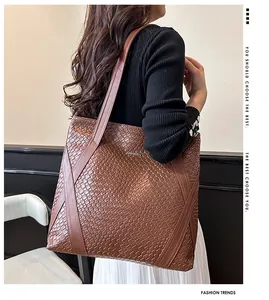 Detail of a large brown woven tote bag featuring a polished JINGPIN metal logo plate