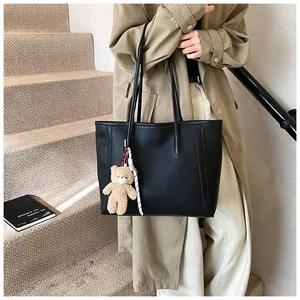 Detailed shot of black litchi pattern tote bag with a cute brown bear charm on strap