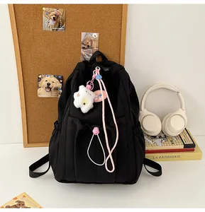 Detalle de mochila escolar de nailon negro con osito de peluche y accesorios rosas