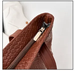 Close-up of smooth gold metal zipper on brown woven leather tote bag with clear texture