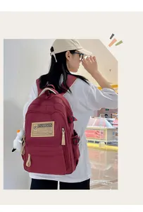 Detalle de la mochila de nailon granate con etiqueta de moda y peluche de pato blanco