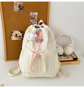 Detalle de mochila de lona blanco roto con cordones rosas y colgante de nube de peluche