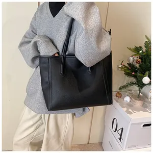 Detailed texture of black lychee grain leather on a spacious tote bag with shoulder straps