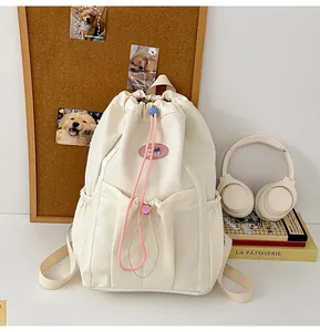 Detalle de mochila crema con cordón, detalles en rosa y bolsillos laterales amplios