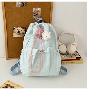 Primer plano de mochila azul claro con cordón, detalles rosas y colgante de nube