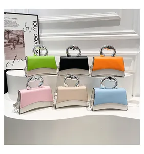 Detalle de bolsos de cuero PU en bloques de colores con asas metálicas únicas y varios tonos