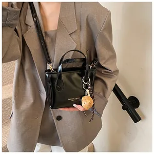 Mini borsa a secchiello in pelle verniciata nera con manico e ciondolo a sfera gialla
