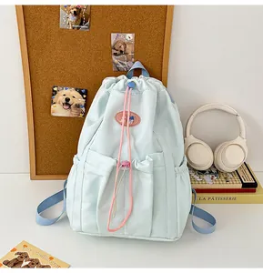 Detalle de mochila verde menta con cordón rosa y bolsillos frontales funcionales