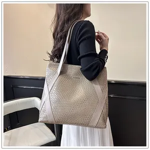 Detailed view of large beige woven tote bag with leather straps on model's shoulder