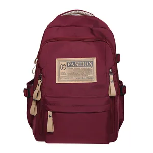 Detalle de una mochila burdeos de gran capacidad con parche retro y hebilla