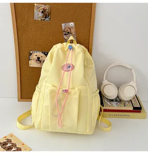 Detalle de mochila de lona amarilla con cordón rosa en contraste y bolsillo lateral práctico