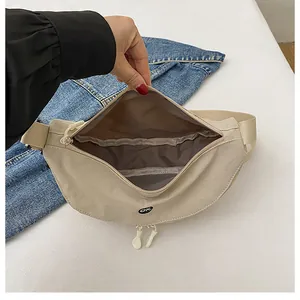Vista detallada de la riñonera de nailon beige con forro interior y bolsillo organizador