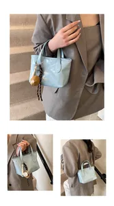 Dettaglio della borsa a secchiello lucida azzurra con scritte moda e ciondolo carino
