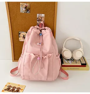 Vista detallada de mochila rosa con cordón, parche ilustrado y bolsillos laterales
