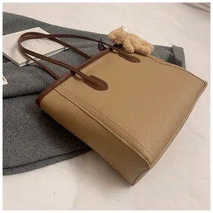 Detail of large tote bag in lychee pattern leather with a cute plush bear charm