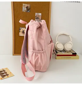 Detalle de mochila rosa con cordón, correas acolchadas de malla y bolsillos laterales